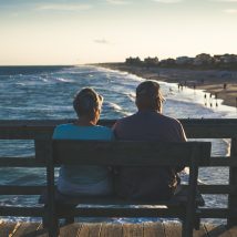 man and woman sitting on bench in front of beach