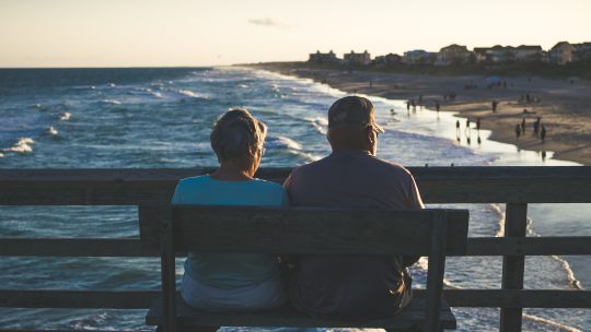 man and woman sitting on bench in front of beach