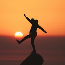 photo of silhouette photo of man standing on rock